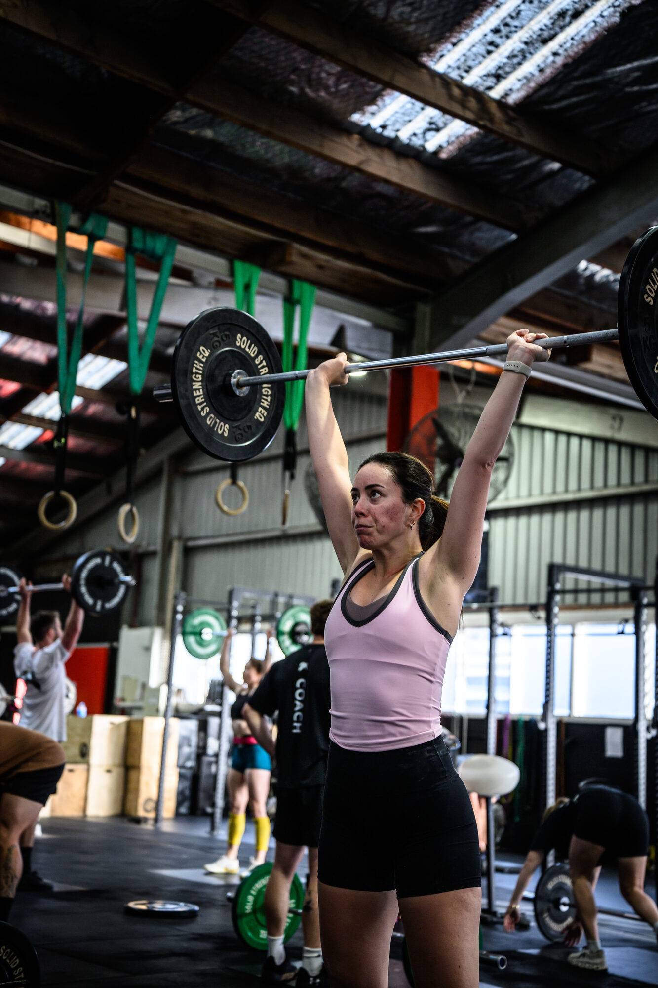 KnoxFit member locking out an overhead press during a group session